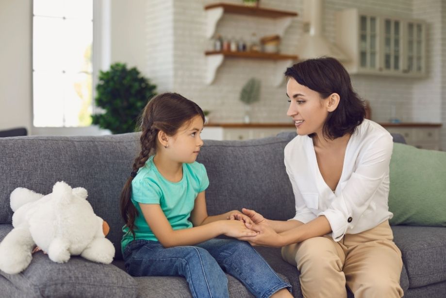 A woman and a young girl sit together on a couch, sharing a moment of joy and connection.